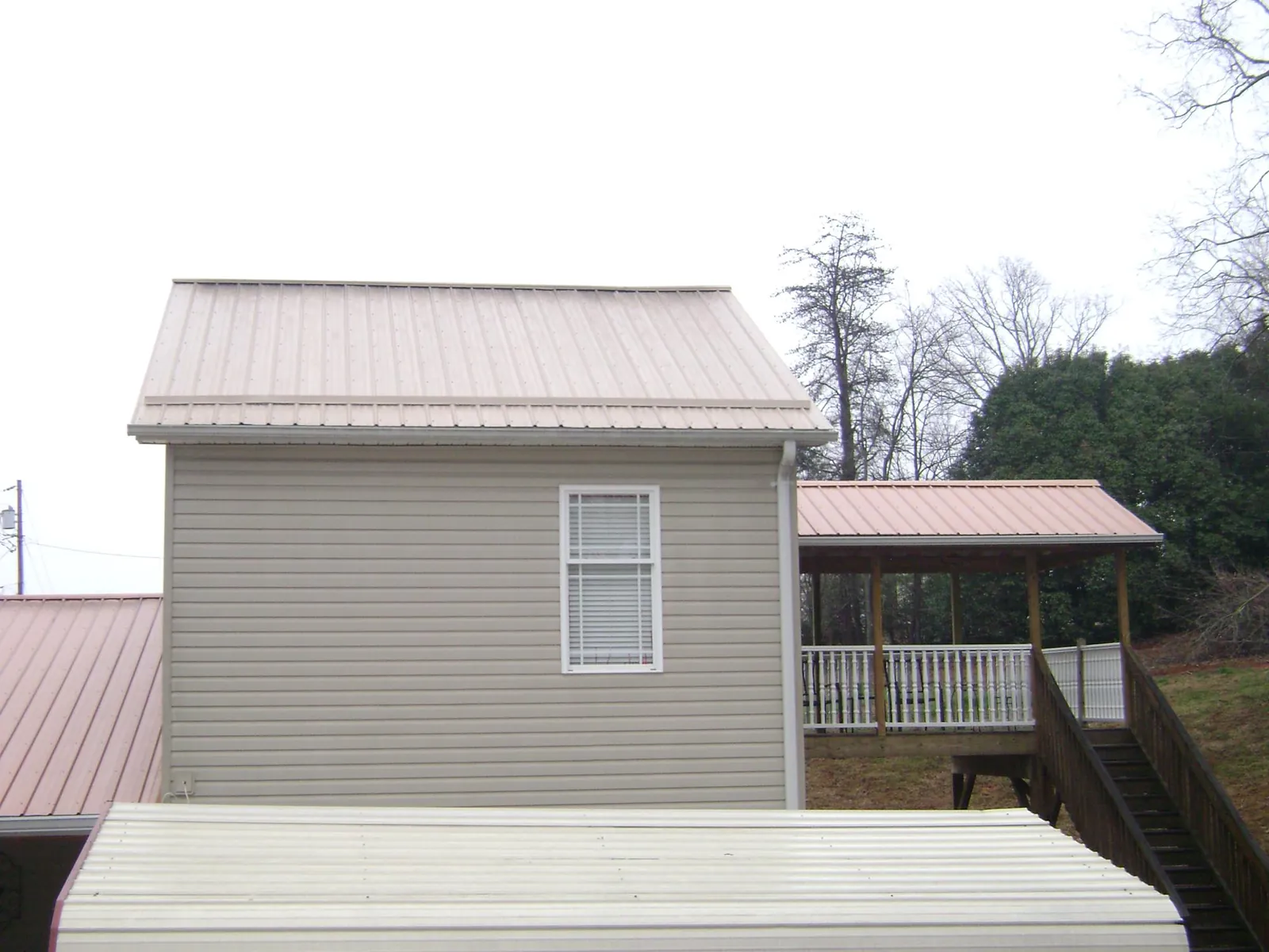 Tan metal roofs on a two story addition and attached porch, from a Roof Replacement job in Mountain View